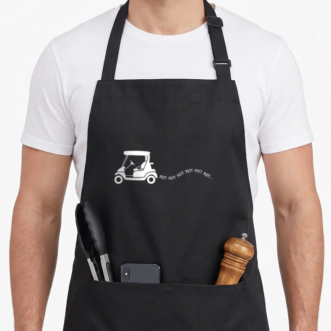 Joke golf apron - White golf cart silhouette with trailing PUTT PUTT text on black background — shown on a black cotton canvas apron against a white background