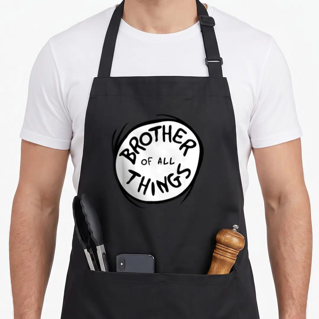 Emblem big brother apron - BROTHER OF ALL THINGS text inside white oval with thick black border — shown on a black cotton canvas apron against a white background