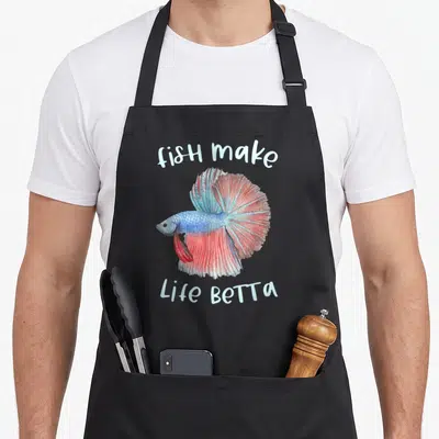Betta aquarium fish apron - Watercolor betta fish in blue and red with arched text fish make Life Betta — shown on a black cotton canvas apron against a white background