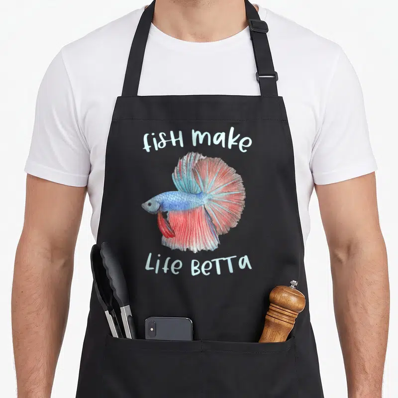 Betta aquarium fish apron - Watercolor betta fish in blue and red with arched text fish make Life Betta — shown on a black cotton canvas apron against a white background