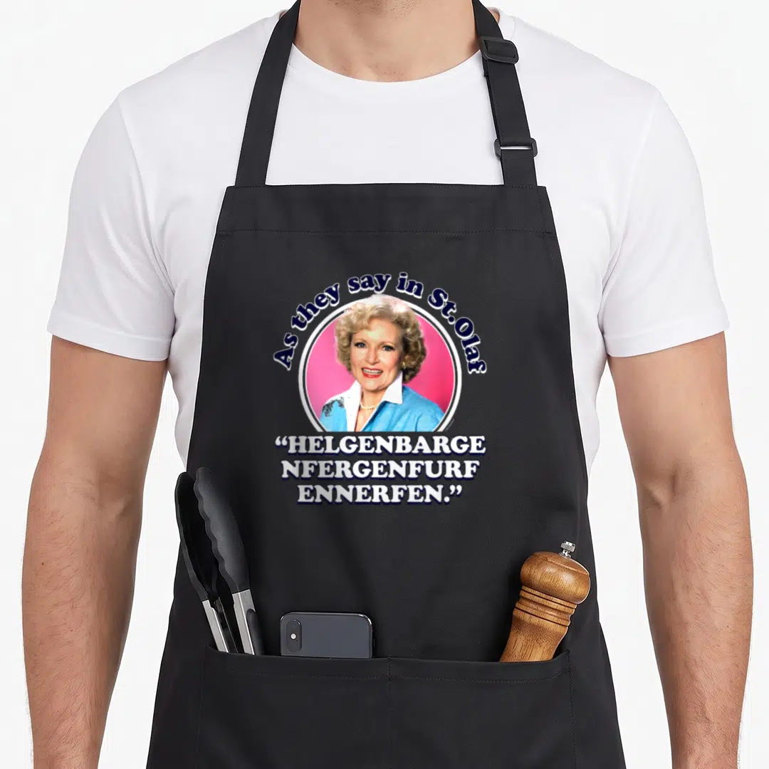 Rose golden apron - Woman photo in pink circle with As they say in St Olaf text and three lines of stacked German-style — shown on a black cotton canvas apron against a white background