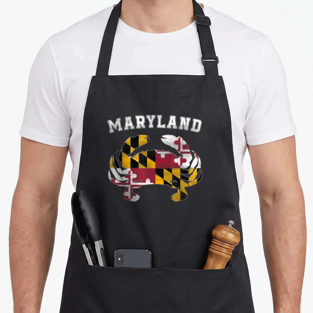 Blue crab apron - Arched MARYLAND text above a crab filled with red yellow black and white flag patterns — shown on a black cotton canvas apron against a white background