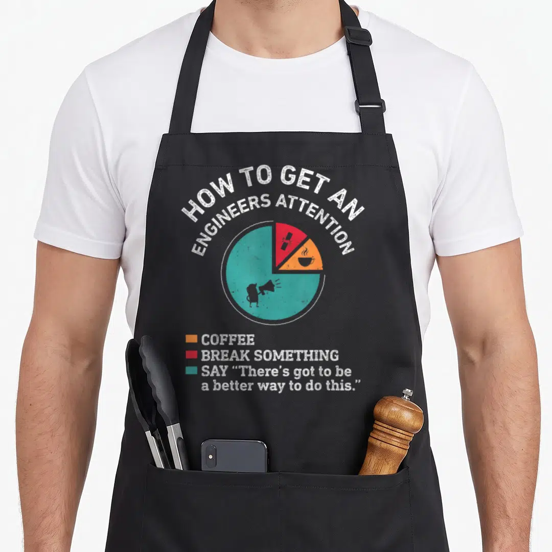 Attention engineering engineer apron - Distressed pie chart with teal red orange sections and text about coffee — shown on a black cotton canvas apron against a white background