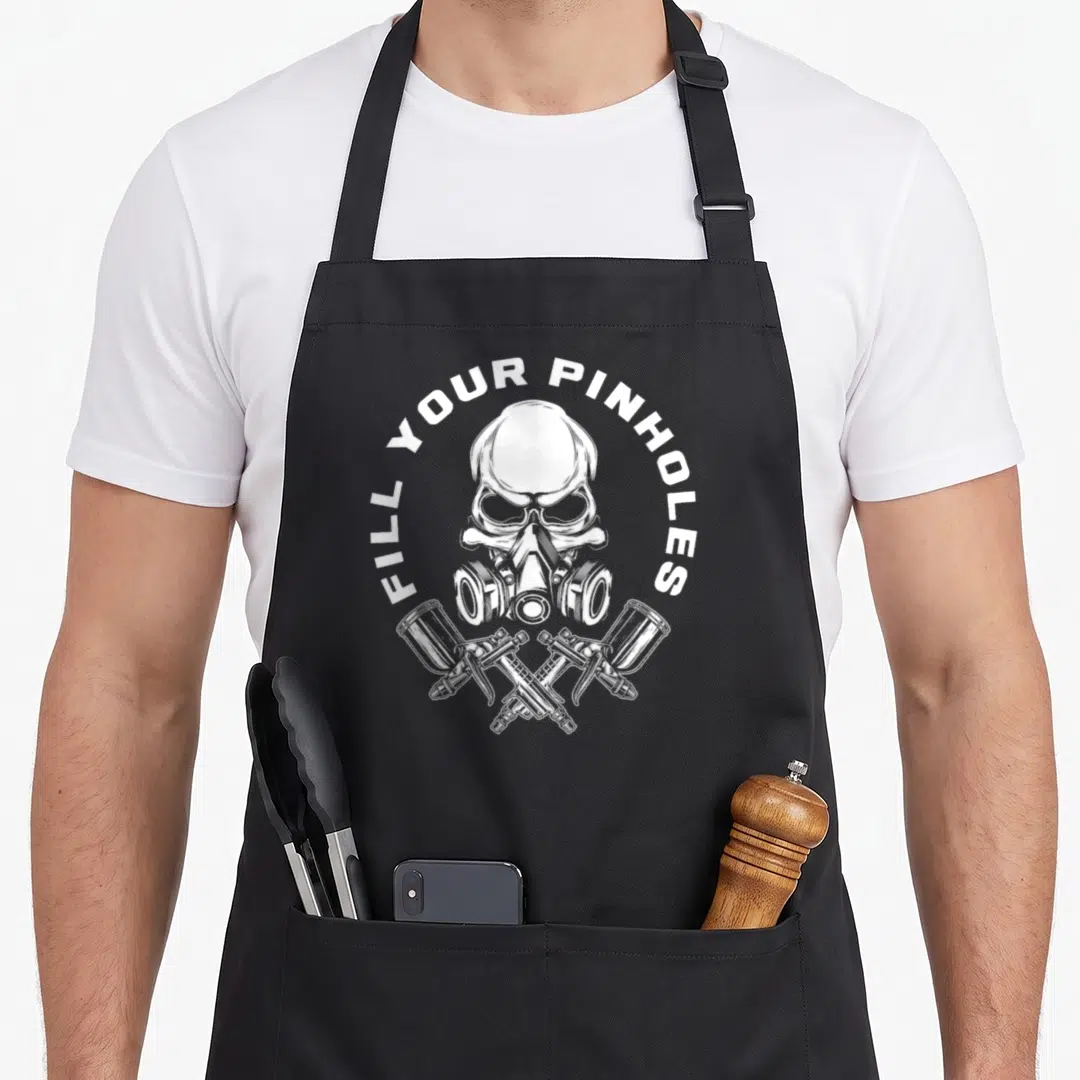 Fill painter apron - White skull in respirator with two crossed spray guns and arched text — shown on a black cotton canvas apron against a white background