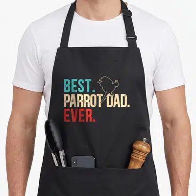 Parrot birdwatching bird apron - Blue beige and red stacked text reading BEST PARROT DAD EVER with parrot outline — shown on a black cotton canvas apron against a white background