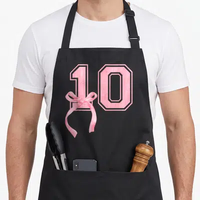 Bow girly apron - Pink number 10 with ribbon bow on black bib apron — shown on a black cotton canvas apron against a white background