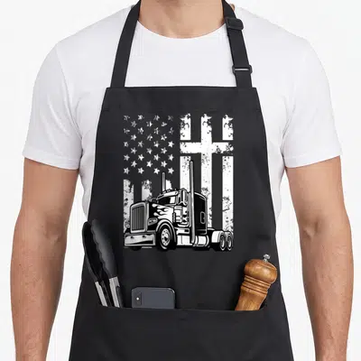 Truck christian american flag apron - Black semi-truck in foreground with distressed white stars and Christian cross — shown on a black cotton canvas apron against a white background