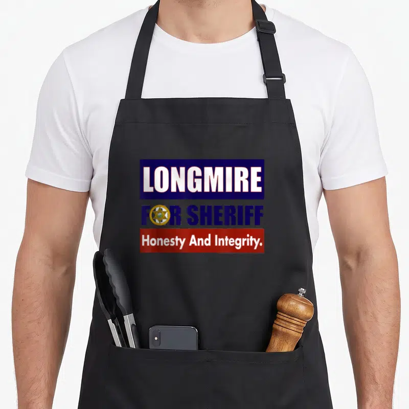 Longmire sheriff apron - Stacked blue and red boxes with LONGMIRE FOR SHERIFF text and a gold star badge icon — shown on a black cotton canvas apron against a white background