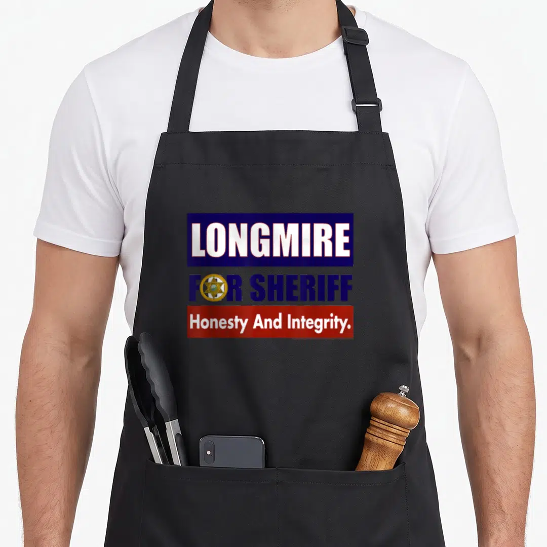 Longmire sheriff apron - Stacked blue and red boxes with LONGMIRE FOR SHERIFF text and a gold star badge icon — shown on a black cotton canvas apron against a white background