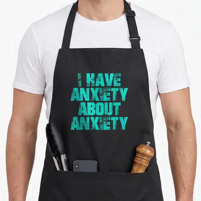 Funny anxiety anxious apron - Stacked teal typography reading I Have Anxiety About Anxiety on grey background — shown on a black cotton canvas apron against a white background