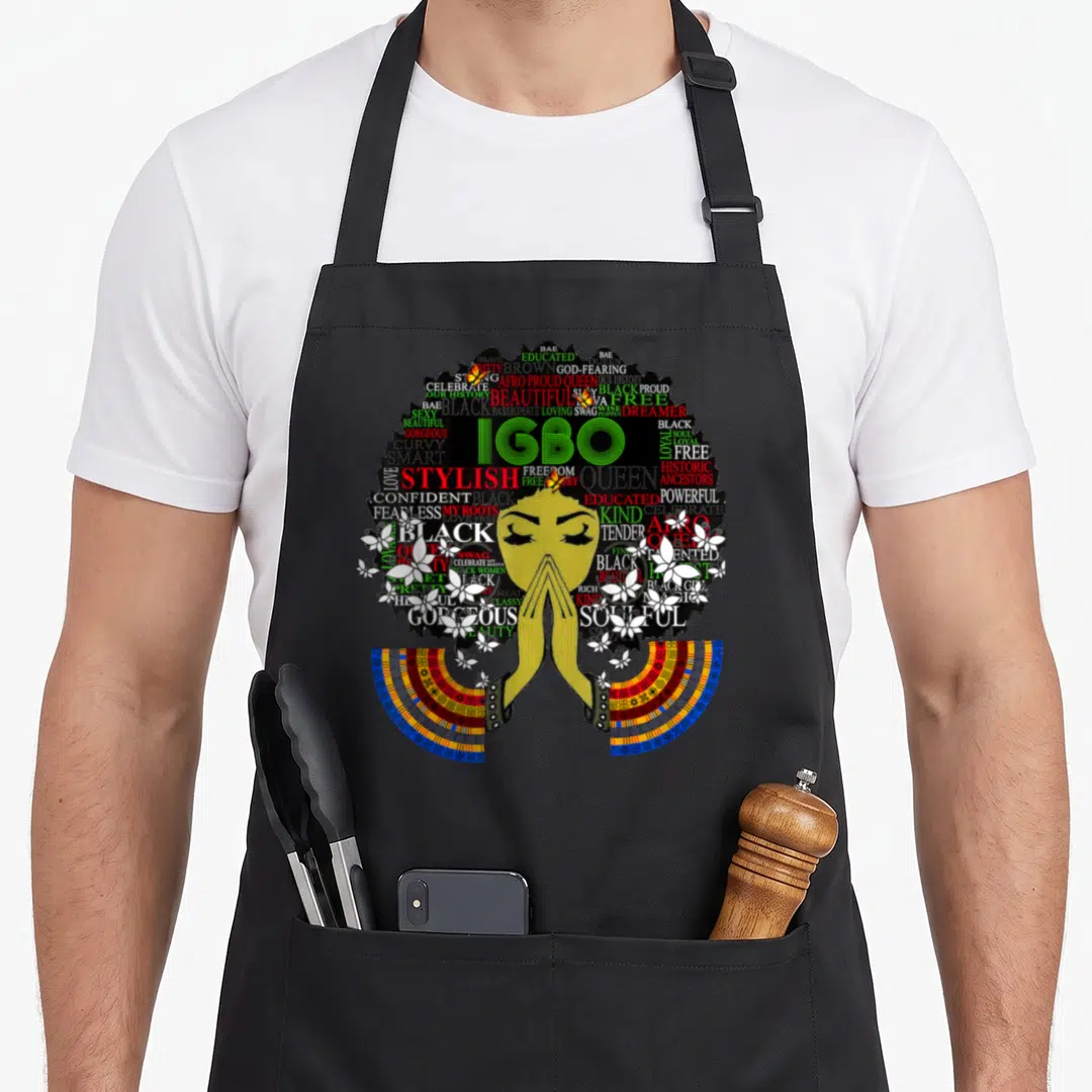 Igbo nigeria nigerian apron - Woman in prayer with afro formed by words like IGBO and BLACK PROUD surrounded by flowers — shown on a black cotton canvas apron against a white background