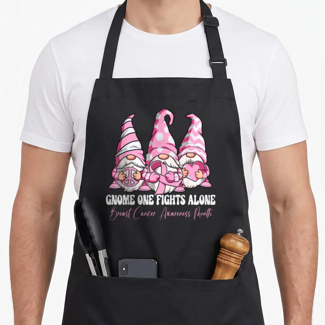 Alone breast cancer awareness aprons - Three pink and white gnomes holding peace sign, ribbon, and heart with text below — shown on a black cotton canvas apron against a white background