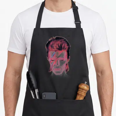 Prettiest david aprons - Stylized male portrait with pink, red, and blue lightning bolt across eyes — shown on a black cotton canvas apron against a white background