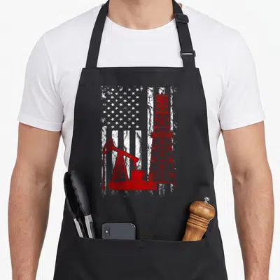Proud english class apron - Red oil rig and pumpjack over distressed white US flag pattern — shown on a black cotton canvas apron against a white background
