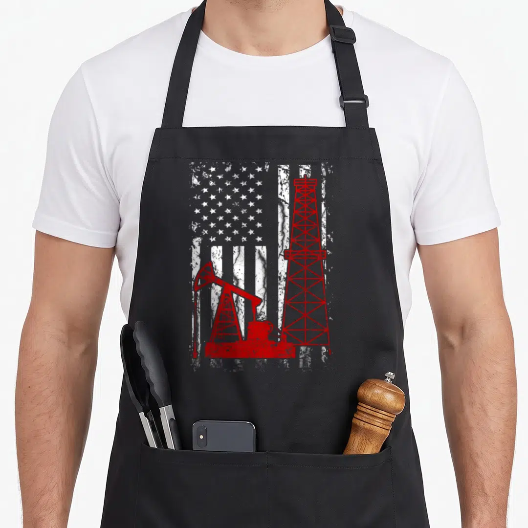 Proud english class apron - Red oil rig and pumpjack over distressed white US flag pattern — shown on a black cotton canvas apron against a white background