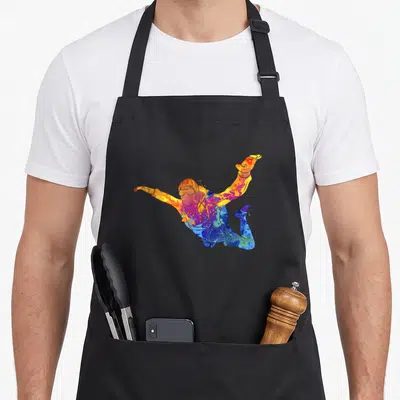 Parachutust skydiving apron - Multicolored watercolor skydiver figure in jumping pose with blue purple orange yellow — shown on a black cotton canvas apron against a white background
