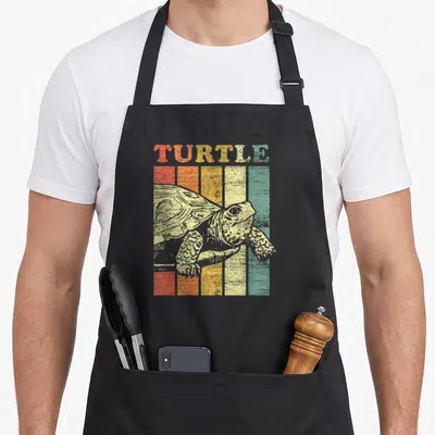 Funny turtle lady apron - Retro sketched turtle over five vertical stripes in red orange yellow green and pale yellow — shown on a black cotton canvas apron against a white background