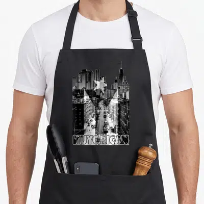 Nuyorican new york apron - Black and white NYC street photo with white star and NUYORICAN text filled with buildings — shown on a black cotton canvas apron against a white background