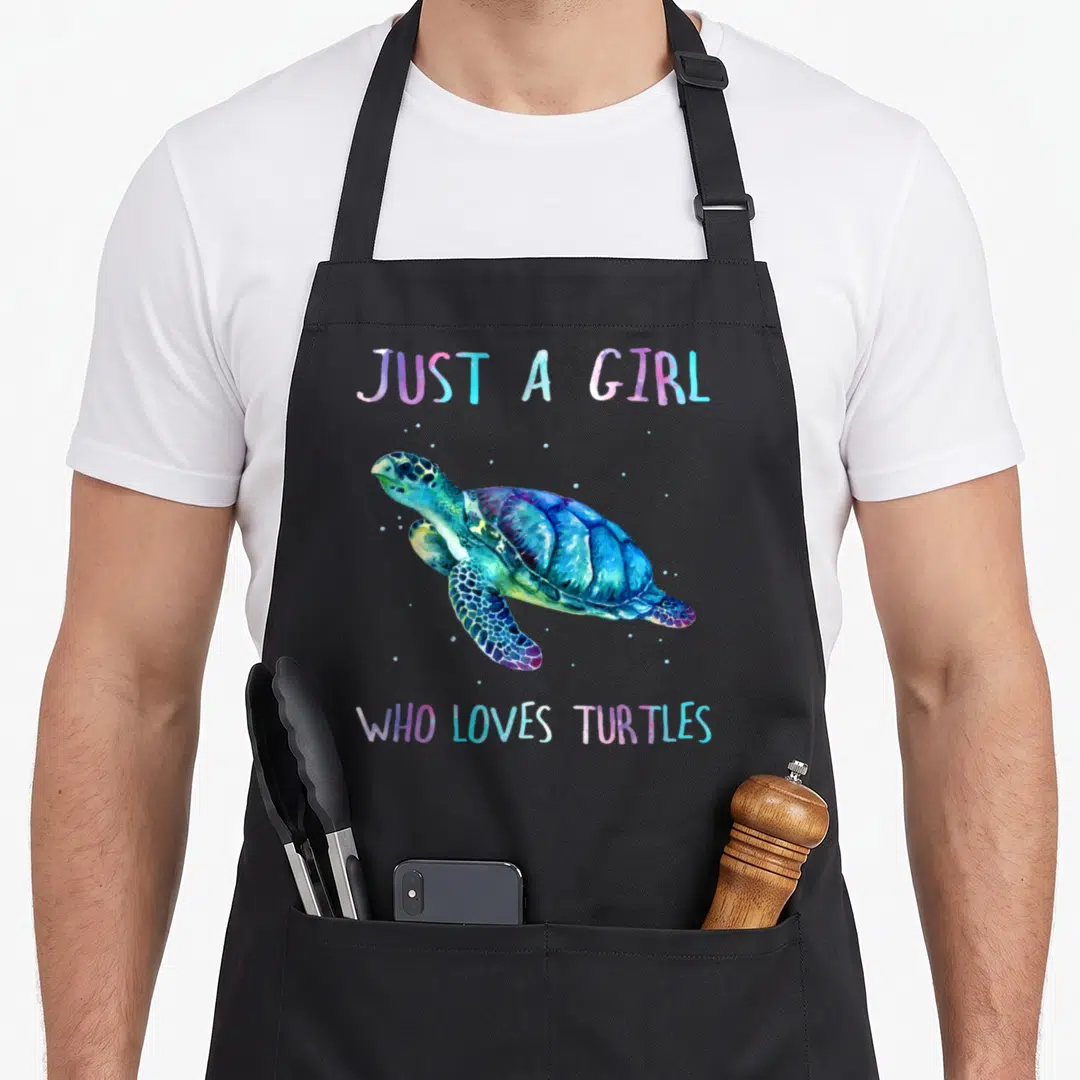 Watercolor turtle dove apron - Sea turtle swimming between Just a Girl Who Loves Turtles text in watercolor blue — shown on a black cotton canvas apron against a white background