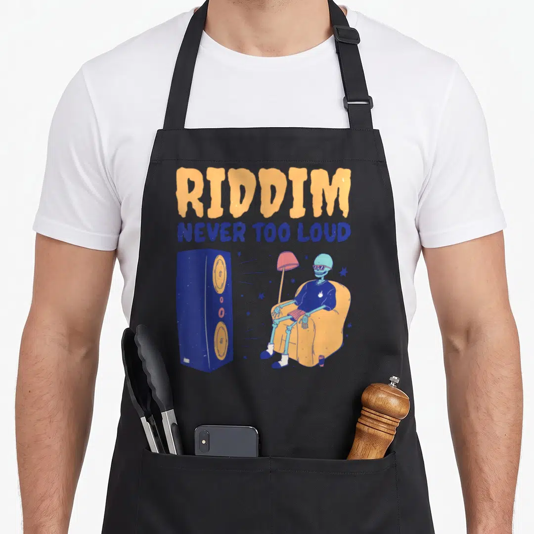 Riddim skeleton apron - Cartoon skeleton in chair next to speaker with stacked text — shown on a black cotton canvas apron against a white background