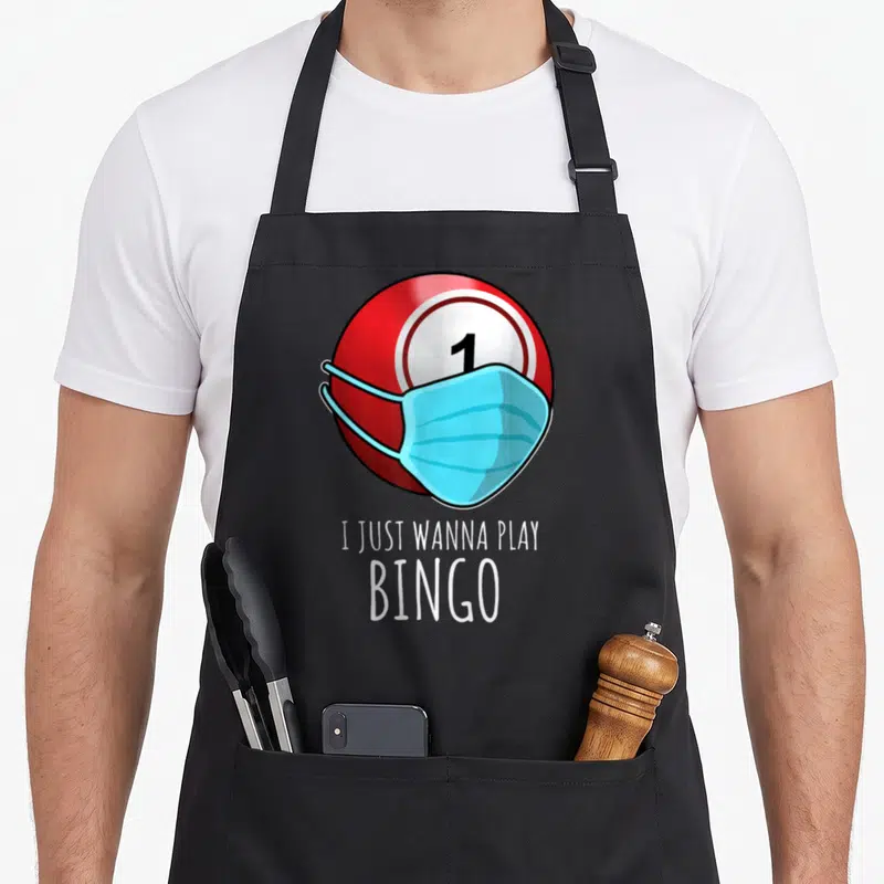Play player bingo apron - Red bingo ball with blue mask and text I Just Wanna Play Bingo — shown on a black cotton canvas apron against a white background