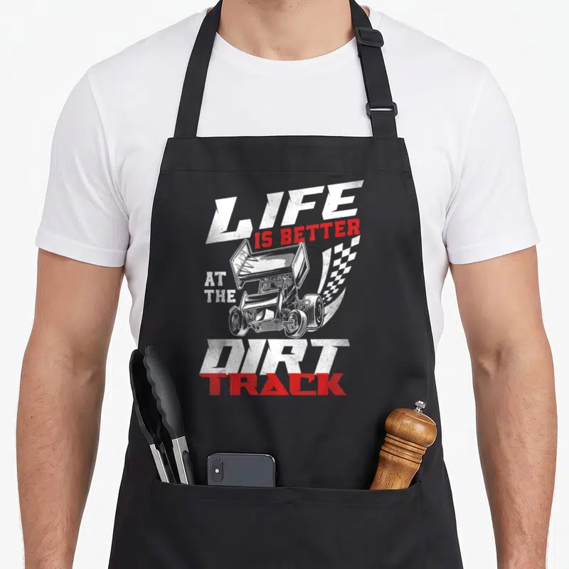 Dirt racing race track apron - Sprint car and checkered flag with LIFE IS BETTER AT THE DIRT TRACK text in distressed — shown on a black cotton canvas apron against a white background