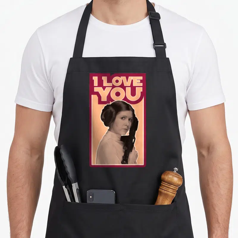 Valentine princess apron - Retro woman holding blaster below I LOVE YOU text in maroon orange frame — shown on a black cotton canvas apron against a white background