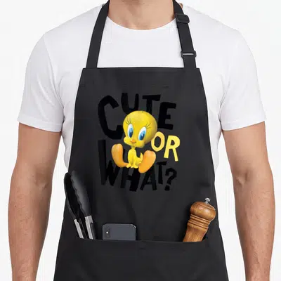 Tweety apron or apron - Yellow cartoon bird sitting over black CUTE OR WHAT? text — shown on a black cotton canvas apron against a white background