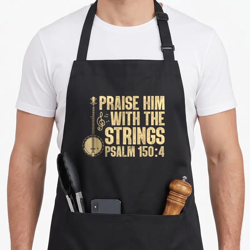 Worship banjo apron - Distressed tan banjo illustration next to stacked Praise Him With The Strings Psalm 150:4 text — shown on a black cotton canvas apron against a white background