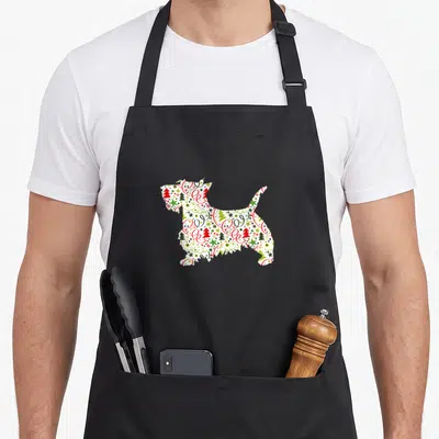 Scottie christmas dog apron - Dog silhouette filled with red green and white Christmas tree swirl and dot patterns — shown on a black cotton canvas apron against a white background