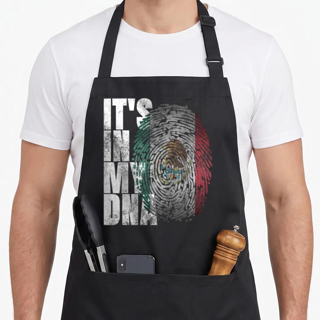 Dna mexico apron - Distressed IT'S IN MY DNA text over a Mexican flag fingerprint pattern — shown on a black cotton canvas apron against a white background