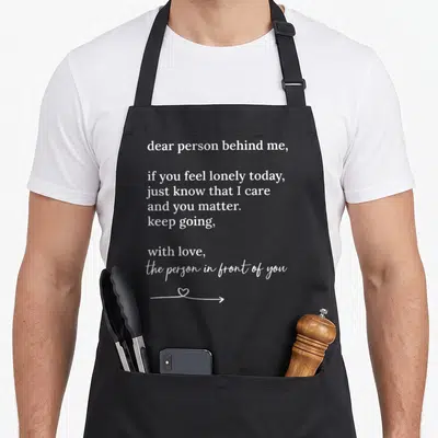 Matter novelty apron - White text saying you matter with a heart integrated into a right-pointing arrow — shown on a black cotton canvas apron against a white background