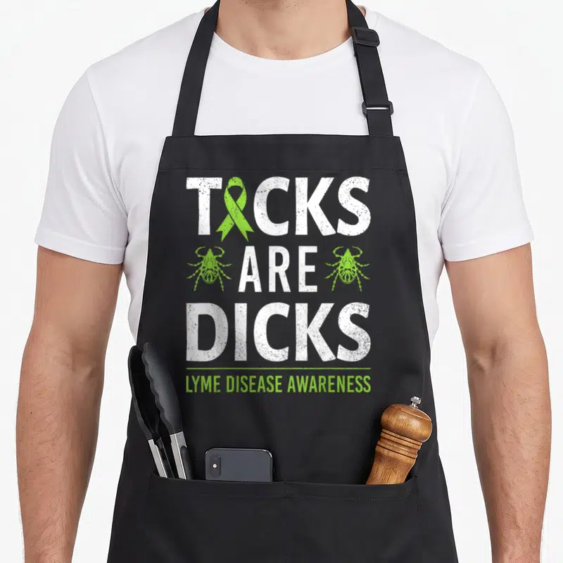 Tick ribbon apron - Distressed white text reading TICKS ARE DICKS with lime green ribbon and two tick icons above Lyme — shown on a black cotton canvas apron against a white background
