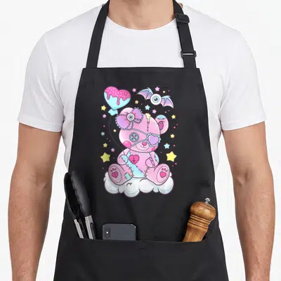 Kawaii bear apron - Pink teddy bear on white cloud with heart balloon and bat surrounded by stars — shown on a black cotton canvas apron against a white background