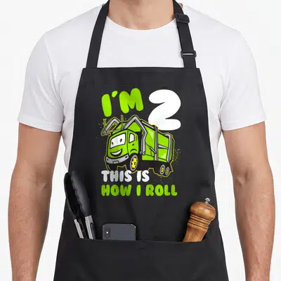 Toddler garbage truck apron - Lime green cartoon garbage truck with text I'M 2 THIS IS HOW I ROLL — shown on a black cotton canvas apron against a white background