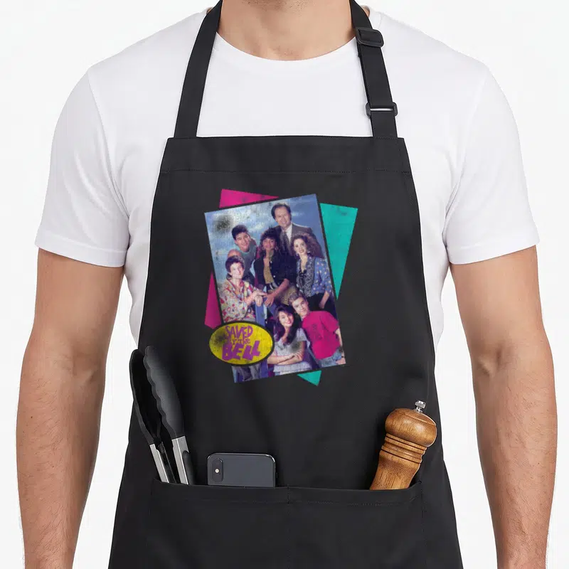 Cast bell apron - Six people photo with pink teal triangles and yellow Saved By The Bell logo oval — shown on a black cotton canvas apron against a white background