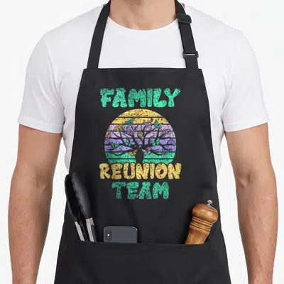 Vintage family gathering apron - Retro tree and butterflies in striped circle with FAMILY REUNION TEAM text — shown on a black cotton canvas apron against a white background