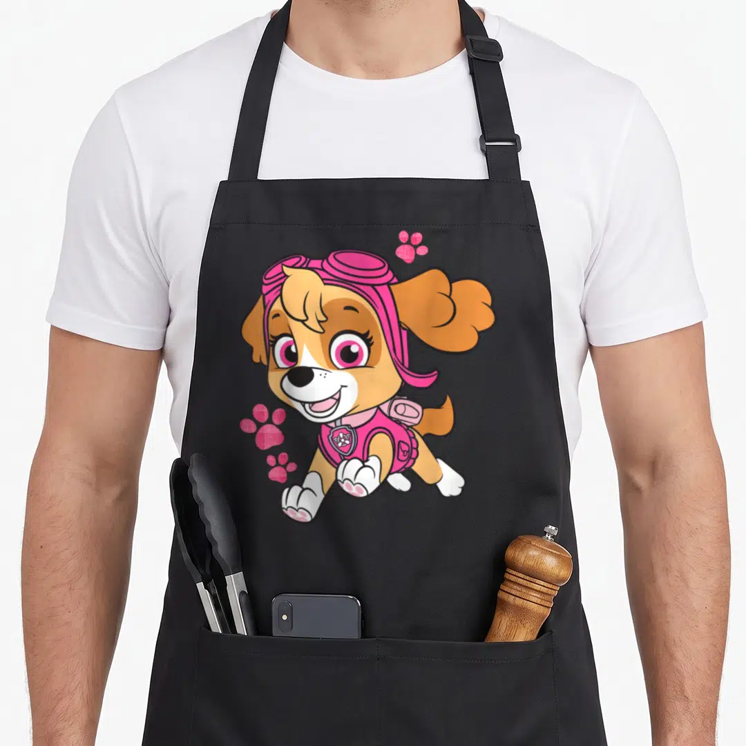 Skye patrol happy apron - Cartoon Skye jumping with three pink glittery paw prints — shown on a black cotton canvas apron against a white background