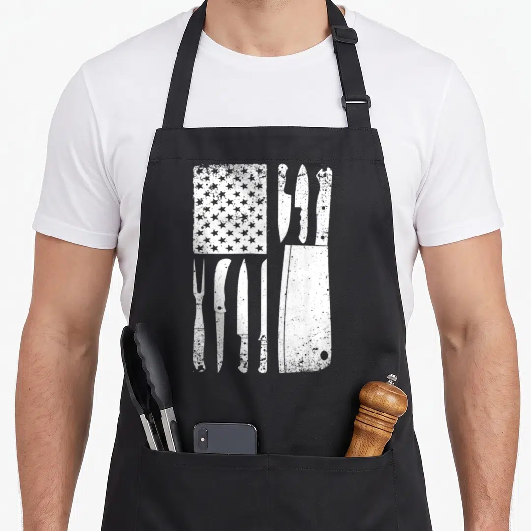 Knife american flag apron - White distressed USA flag formed by arrangement of surgical knives and forceps — shown on a black cotton canvas apron against a white background