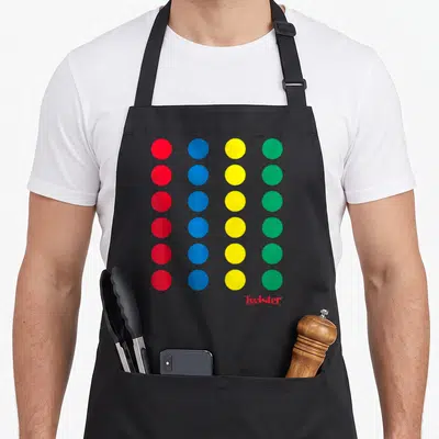 Twister halloween apron - Grid of red blue yellow green dots with Twister logo and copyright text below — shown on a black cotton canvas apron against a white background