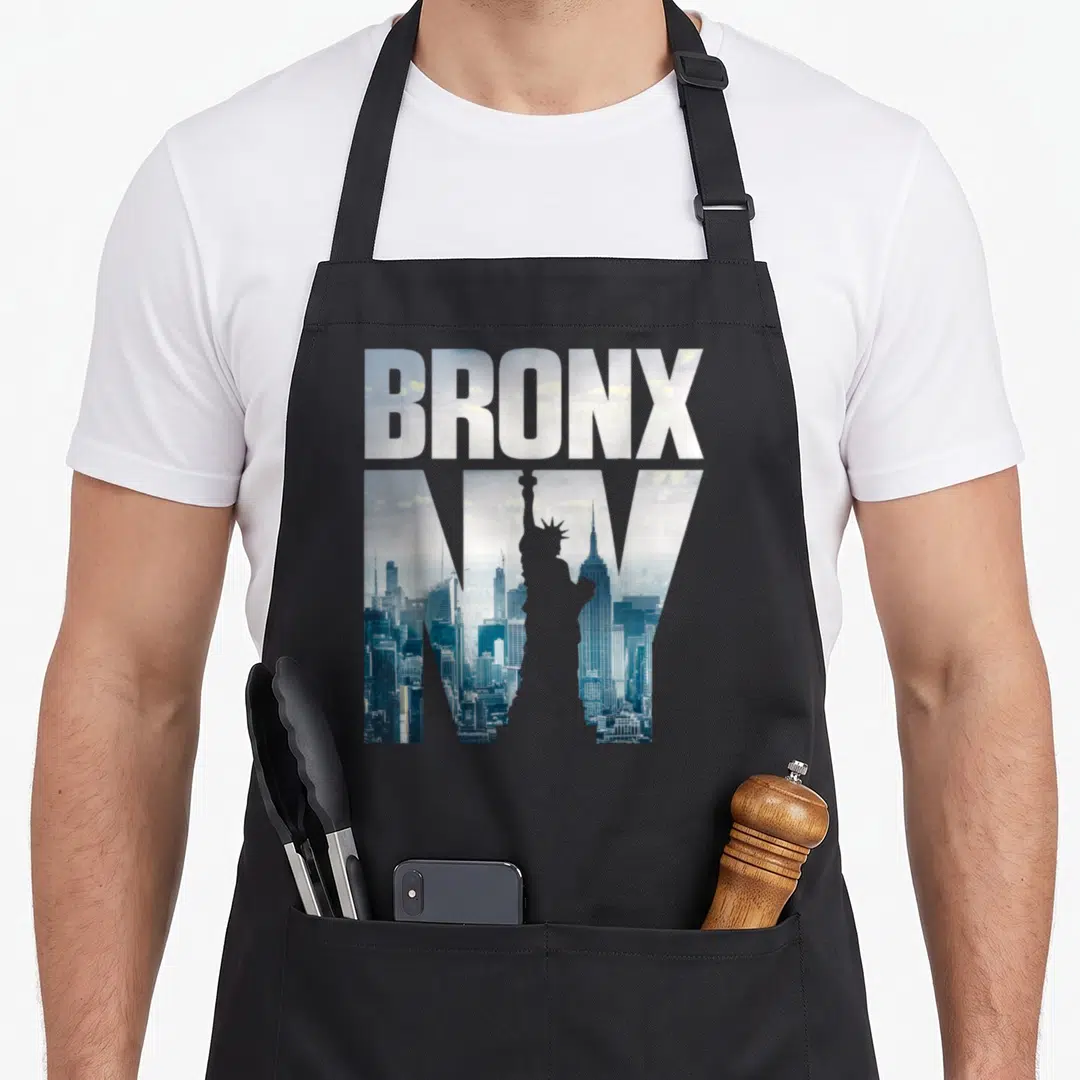 Illustration new york apron - BRONX NY text filled with NYC skyline photo and Statue of Liberty silhouette in blue — shown on a black cotton canvas apron against a white background