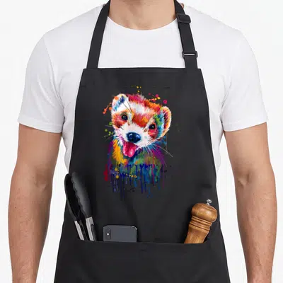 Ferret face apron - Multicolored watercolor ferret head with blue red yellow purple orange paint splatters and drips — shown on a black cotton canvas apron against a white background