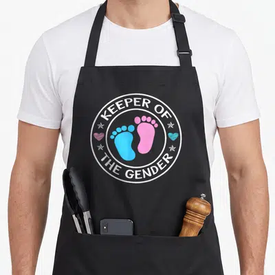 Keeper baby shower apron - Blue and pink baby footprints inside white circle with hearts and stars — shown on a black cotton canvas apron against a white background