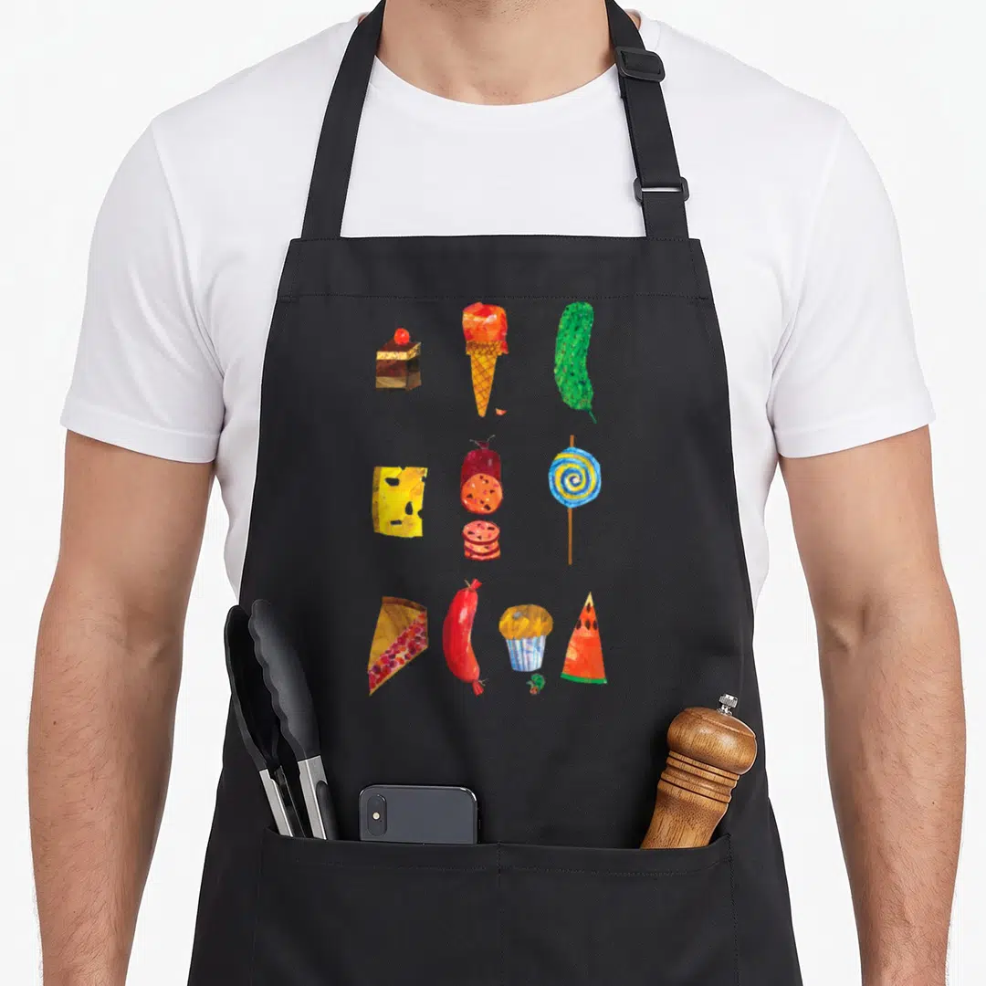 Retro food aprons - Watercolor food grid with cake, ice cream, cheese, salami, lollipop, cupcake, and small green — shown on a black cotton canvas apron against a white background