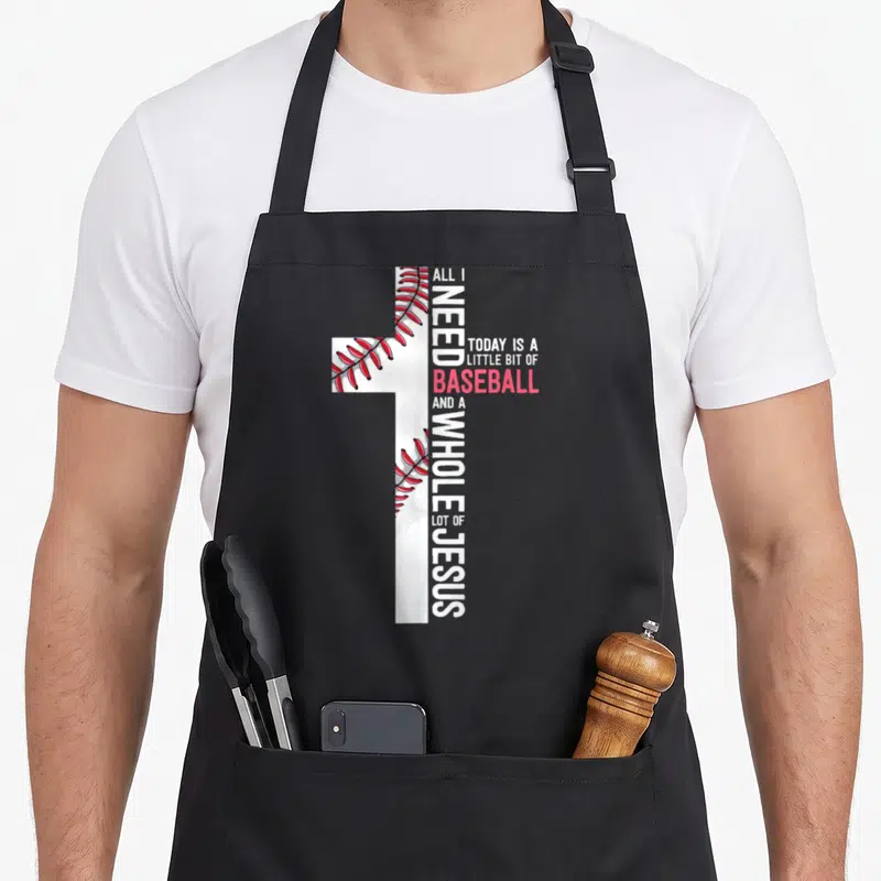 Baseball jesus christian apron - White cross with red stitching and vertical text reading ALL I NEED TODAY IS A LITTLE — shown on a black cotton canvas apron against a white background