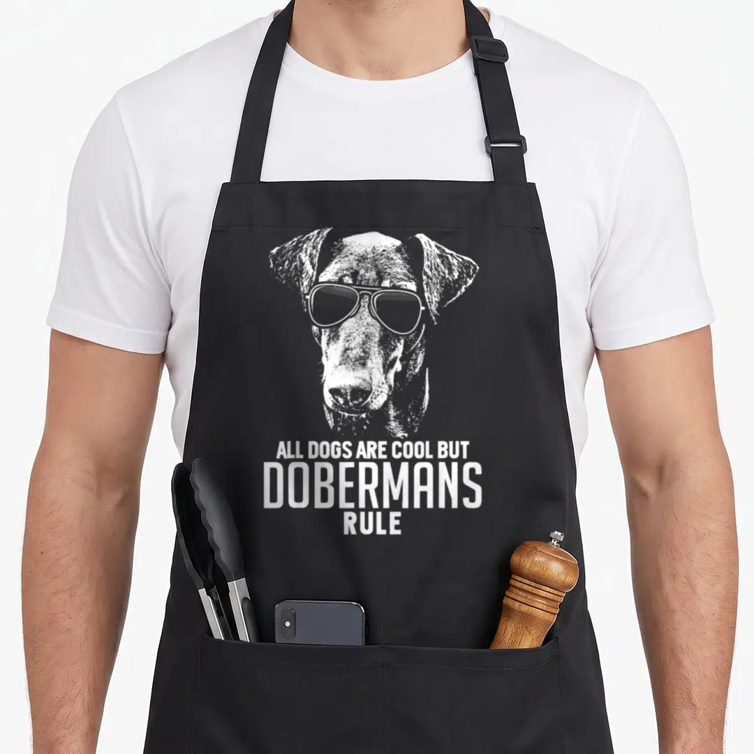 Doberman dog rules apron - White distressed doberman head with sunglasses above stacked text on black apron — shown on a black cotton canvas apron against a white background