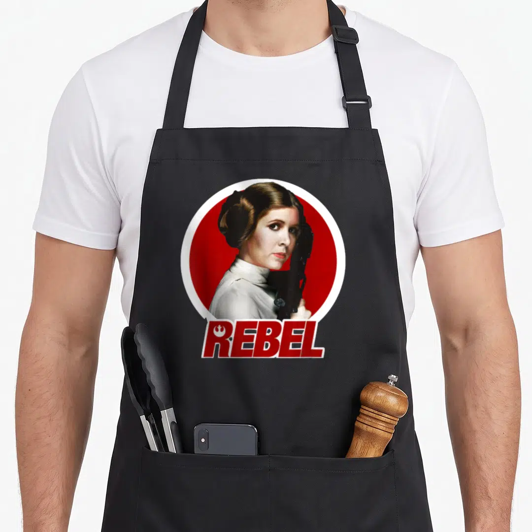 Original princess apron - Princess Leia portrait in red circle with REBEL text below — shown on a black cotton canvas apron against a white background