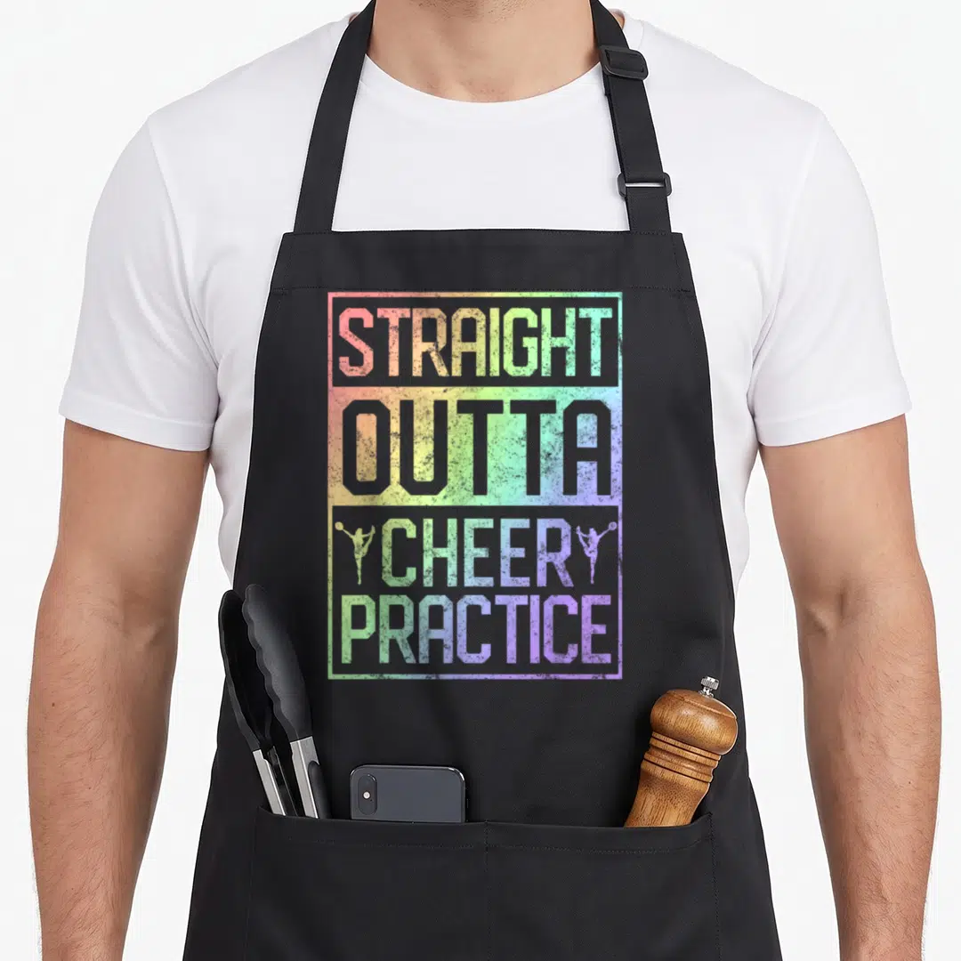 Straight cheer apron - Rainbow gradient text STRAIGHT OUTTA CHEERY PRACTICE with cheerleader silhouettes — shown on a black cotton canvas apron against a white background