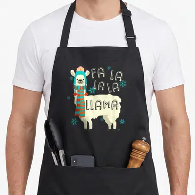 Llama christmas alpaca apron - Cartoon cream llama in blue hat and striped scarf next to Fa La La Llama text and blue — shown on a black cotton canvas apron against a white background
