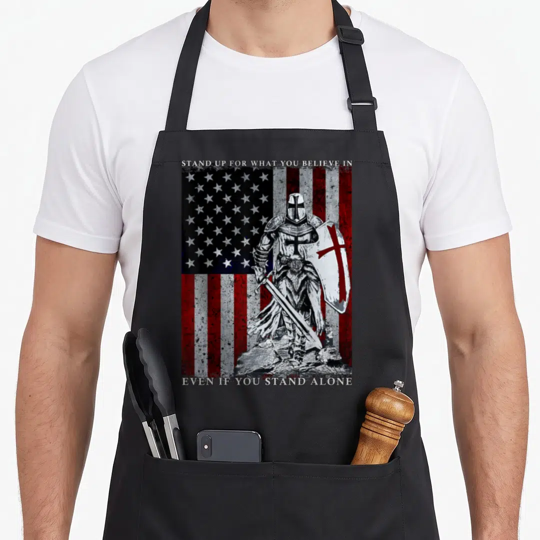 Templar american flag apron - Knight holding sword and cross shield in front of distressed American flag with text — shown on a black cotton canvas apron against a white background